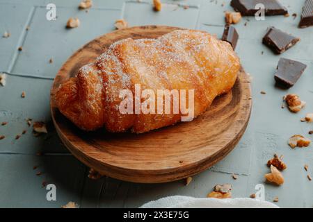 Ein xuixo de Crema, ein Gebäck gefüllt mit Pudding typisch für katalonien, spanien, auf einem Holzteller auf einer strukturierten grauen Oberfläche Stockfoto