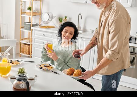 Eine behinderte Frau im Rollstuhl und ihr Mann zusammen in ihrer Küche zu Hause, umgeben von Liebe und Wärme. Stockfoto