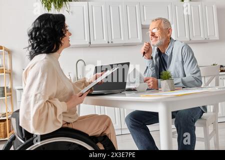 Ein Mann und eine Frau im Rollstuhl plaudern in der Küche zu Hause. Stockfoto