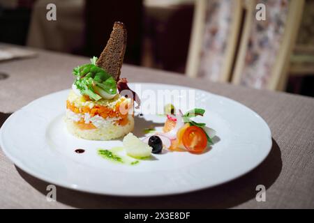 Mehrschichtiger Salat in runder Form, dekoriert mit Brot auf Teller im Restaurant Stockfoto