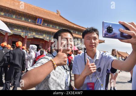 Peking, China. April 2024. Ein Schüler (L) der Delegation der Muskatinen-High-School macht Selfies im Palace Museum in Peking, der Hauptstadt Chinas, am 18. April 2024. Insgesamt 32 Schüler und acht Lehrer der Muscatine High School im US-Bundesstaat Iowa besuchten kürzlich eine einwöchige Studienreise nach Peking, Hebei und Shanghai. Die Delegation der Muscatine High School ist Teil eines von China initiierten Programms, das innerhalb von fünf Jahren 50.000 amerikanische Jugendliche zum Austausch und zum Studium nach China einladen wird. Die Delegation ist der zweite Teil der Schule. Quelle: Liu Zunshuan/Xinhua/Alamy Live News Stockfoto