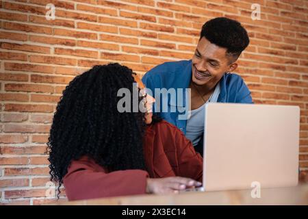 Glückliche multiethnische Männer und Frauen unterhalten sich und surfen im Internet auf einem Laptop. Stockfoto