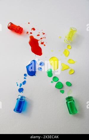 Flaschen mit verschütteter grüner, blauer, roter und gelber Tinte Stockfoto