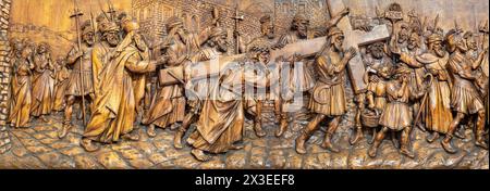 MAILAND, ITALIEN - 5. MÄRZ 2024: Das geschnitzte Relief Simon von Kyrene hilft Jesus, das Kreuz in der Kirche Chiesa di San Camillo zu tragen Stockfoto