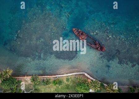 Blick von oben auf ein rostiges Schiffswrack im türkisfarbenen Wasser in der Nähe der tropischen Küste. Drohnenfoto. Sanma, Vanuatu Stockfoto
