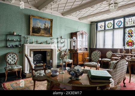 Antikes Mobiliar und Buntglasfenster im Salon in Speke Hall, das unter Denkmalschutz des National Trust Tudor Manor House, Liverpool, England, Großbritannien. Stockfoto