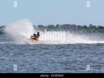 Babylon, New York, USA - 10. Juli 2023: Ein Mann fährt geschickt mit einem Jet Ski auf einem Wasserkörper und erzeugt beim Manövrieren durch das G Spritzer Stockfoto