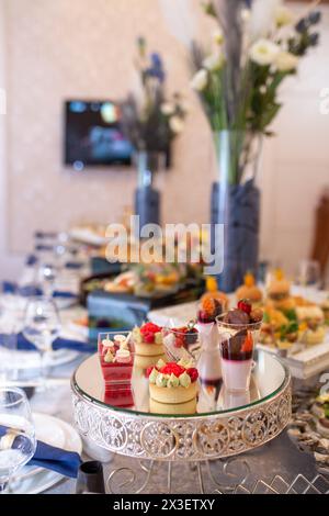 Eine atemberaubende Auswahl an Gebäck und Desserts, sorgfältig auf einem Spiegeltablett angeordnet, ideal für elegante Veranstaltungen und Versammlungen. Stockfoto