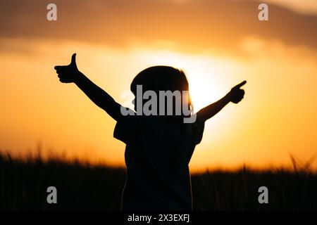 Silhouette eines positiven kleinen Jungen mit den Händen, Zeichen wie, Daumen hoch Geste. Glücklich Stockfoto