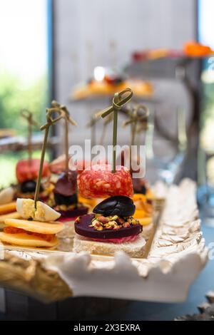 Eine Auswahl an köstlichen Spießen auf einer weißen Platte für das Catering, einschließlich Salami, Käse, Oliven und mehr. Stockfoto