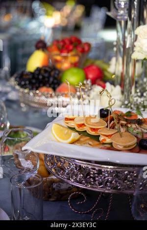 Nahaufnahme einer Vielzahl von Vorspeisen und Obst auf einem Catering-Banketttisch mit selektivem Fokus auf die vorderen Vorspeisen Stockfoto