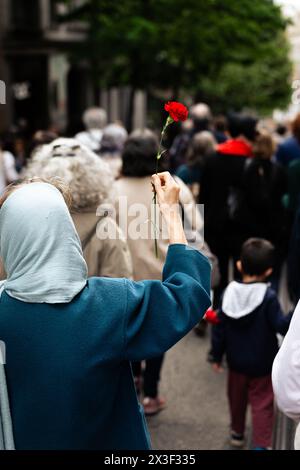 Porto, Portugal. April 2024. Eine Frau hält eine Nelke während des 50. Jahrestages der Nelkenrevolution Parade in den Straßen von Porto. Tausende von Menschen nahmen an den Feierlichkeiten zum 50. Jahrestag des 25. April in Porto Teil. Am 25. April 1974 beendete eine militärische Revolution, die als Nelkenrevolution bekannt war, die Diktatur des Estado Novo und stellte die Demokratie in Portugal wieder her. Seitdem wird dieser Tag als Freiheitstag gefeiert. Quelle: SOPA Images Limited/Alamy Live News Stockfoto