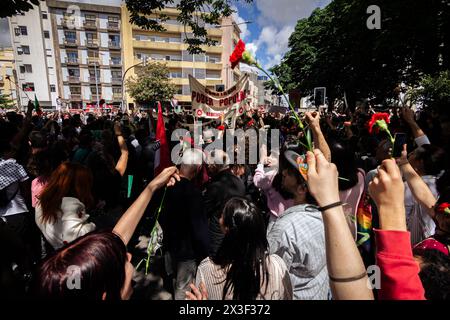 Porto, Portugal. April 2024. Menschen, die mit Nelken während des 50. Jahrestages der Nelkenrevolution Parade in Porto gesehen wurden. Tausende von Menschen nahmen an den Feierlichkeiten zum 50. Jahrestag des 25. April in Porto Teil. Am 25. April 1974 beendete eine militärische Revolution, die als Nelkenrevolution bekannt war, die Diktatur des Estado Novo und stellte die Demokratie in Portugal wieder her. Seitdem wird dieser Tag als Freiheitstag gefeiert. Quelle: SOPA Images Limited/Alamy Live News Stockfoto