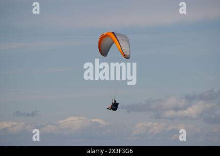 Gleitschirmflieger vor blauem bewölktem Himmel. Stockfoto