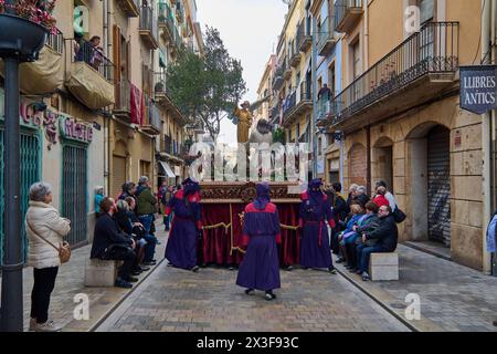 Tarragona, Spanien - 26. April 2024: Karwochenprozession in Tarragona, bei der Einzelpersonen in Gewändern mit einem Wagen mit religiösen Figuren umgeben sind Stockfoto