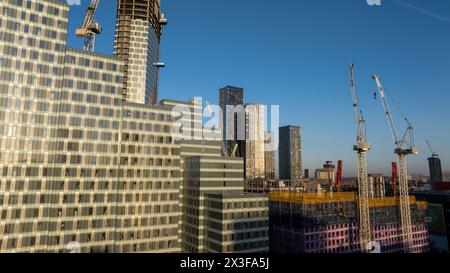 Eine dynamische Stadtbaustelle mit hohen Glashochhäusern und leuchtendem blauem Himmel im Hintergrund Stockfoto