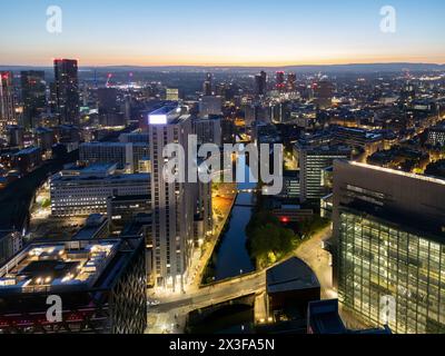 Atemberaubender Blick aus der Vogelperspektive auf die Stadt am Fluss mit glitzernden Lichtern, die während der Dämmerung vom Wasser reflektiert werden Stockfoto