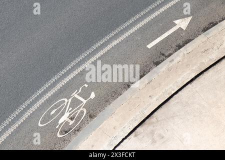 Straßenmarkierungen mit Pfeil und Fahrradsymbol auf der Straße und auf dem Bürgersteig von oben Stockfoto