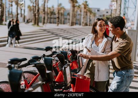 Junge Paare, die einen luftigen Tag mit Fahrrädern von einer Verleihstation in Barcelona verbringen. Stockfoto