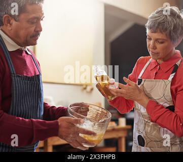Backen, zu Hause und reife Paare in der Küche mit Vorbereitung auf Mittagessen, Abendessen und Abendessen zusammen. Ehe, Liebe und Mann und Frau mit Nahrung, Öl und Stockfoto
