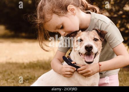 Das kleine Mädchen zieht ihr Hundehalsband an, um spazieren zu gehen Stockfoto