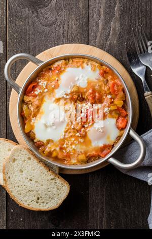 Shakshuka mit Eiern, Tomaten und Petersilie in einer gusseisernen Pfanne. Stockfoto
