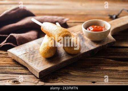 Maishunde oder Wurst in Brötchen mit Ketchup. Tischszene mit Draufsicht über einem Holzhintergrund. Stockfoto