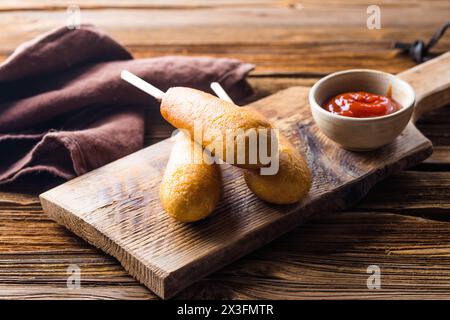 Maishunde oder Wurst in Brötchen mit Ketchup. Tischszene mit Draufsicht über einem Holzhintergrund. Stockfoto