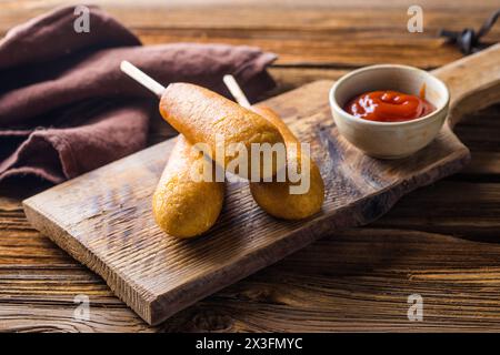 Maishunde oder Wurst in Brötchen mit Ketchup. Tischszene mit Draufsicht über einem Holzhintergrund. Stockfoto