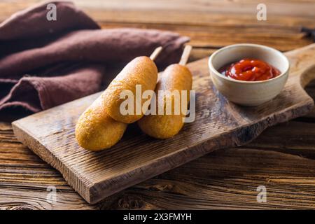 Maishunde oder Wurst in Brötchen mit Ketchup. Tischszene mit Draufsicht über einem Holzhintergrund. Stockfoto