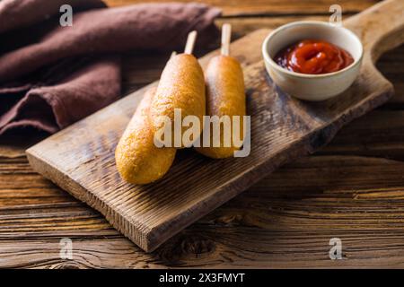 Maishunde oder Wurst in Brötchen mit Ketchup. Tischszene mit Draufsicht über einem Holzhintergrund. Stockfoto