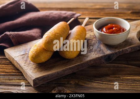 Maishunde oder Wurst in Brötchen mit Ketchup. Tischszene mit Draufsicht über einem Holzhintergrund. Stockfoto