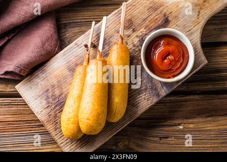 Maishunde oder Wurst in Brötchen mit Ketchup. Tischszene mit Draufsicht über einem Holzhintergrund. Stockfoto