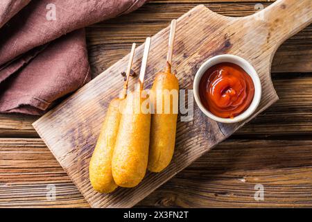 Maishunde oder Wurst in Brötchen mit Ketchup. Tischszene mit Draufsicht über einem Holzhintergrund. Stockfoto