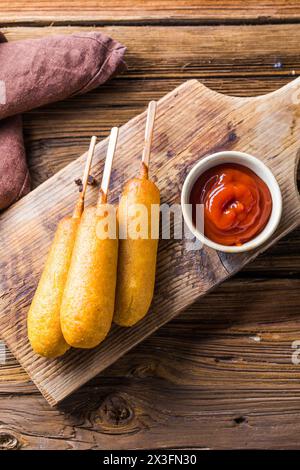 Maishunde oder Wurst in Brötchen mit Ketchup. Tischszene mit Draufsicht über einem Holzhintergrund. Stockfoto