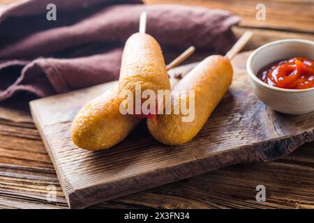 Maishunde oder Wurst in Brötchen mit Ketchup. Tischszene mit Draufsicht über einem Holzhintergrund. Stockfoto