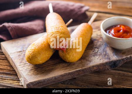 Maishunde oder Wurst in Brötchen mit Ketchup. Tischszene mit Draufsicht über einem Holzhintergrund. Stockfoto