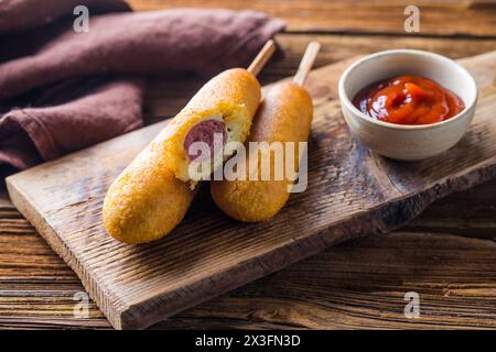 Maishunde oder Wurst in Brötchen mit Ketchup. Tischszene mit Draufsicht über einem Holzhintergrund. Stockfoto