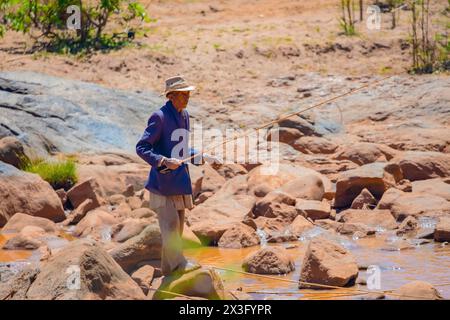 Antananarivo, Madagaskar 07. Oktober 2023. Ein älterer Mann fängt Fische für seine Tochter in einem kleinen Bach Stockfoto