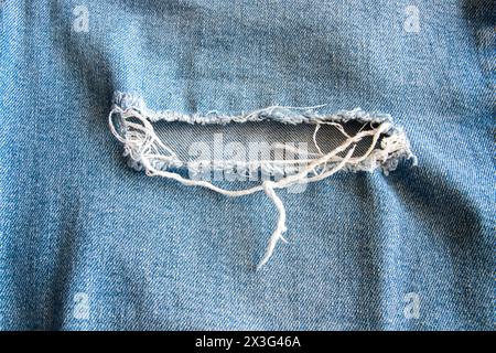 Blaue Jeans, Baumwollkleidung mit sanfter Textur. Textilinhalt. Denim mit Löchern und Tageslicht. Stockfoto