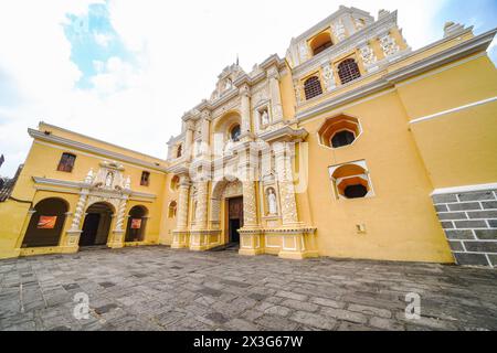 Außenfassade der Kirche und des Konvents von La Merced, einer kunstvoll verzierten katholischen Kirche, die 1749 im Churrigueresque-Stil in Antigua, Guatemala, erbaut wurde. Das hellgelb verzierte Gebäude zeigt Reliefdetails in arabesken Mustern, die Ataurique Stucco genannt werden. Stockfoto