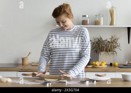 Lächelnde junge Frau, die allein in der modernen Küche kocht Stockfoto