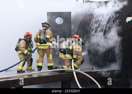 Die Feuerwehrleute der Youngstown Air Reserve Station sprühen Wasser durch die Tür des Flugpersonals, während sie auf einen Flugzeugabsturz auf dem Feuerwehrübungsbereich reagieren, während einer Übung in der Youngstown Air Reserve Station, Ohio, 25. April 2024. Der Schulungsbereich bietet Feuerwehrleuten der Feuerwehr der Anlage, anderer Verteidigungsministerien und umliegender Gemeinden die Möglichkeit, an lebenden Bränden auf dem Apparat zu trainieren, der die Konstruktion verschiedener Flugzeugtypen in der Gegend nachbildet. (Foto der U.S. Air Force von Eric M. White) Stockfoto