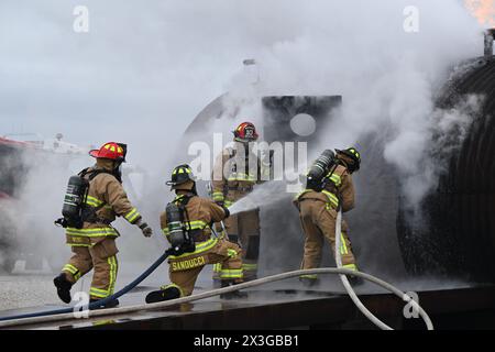 Die Feuerwehrleute der Youngstown Air Reserve Station sprühen Wasser durch die Tür des Flugpersonals, während sie auf einen Flugzeugabsturz auf dem Feuerwehrübungsbereich reagieren, während einer Übung in der Youngstown Air Reserve Station, Ohio, 25. April 2024. Der Schulungsbereich bietet Feuerwehrleuten der Feuerwehr der Anlage, anderer Verteidigungsministerien und umliegender Gemeinden die Möglichkeit, an lebenden Bränden auf dem Apparat zu trainieren, der die Konstruktion verschiedener Flugzeugtypen in der Gegend nachbildet. (Foto der U.S. Air Force von Eric M. White) Stockfoto