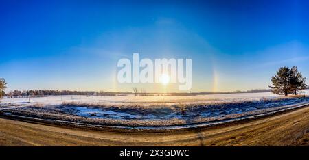 Atmosphärisches optisches Phänomen Sonnenhunde am Morgen über einem Schneefeld. Stockfoto