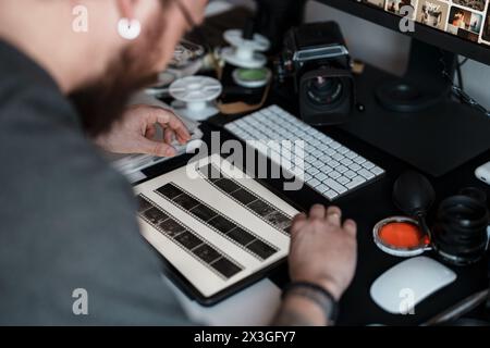 Fotograf, der Filmnegative in einem kreativen Arbeitsbereich überprüft Stockfoto