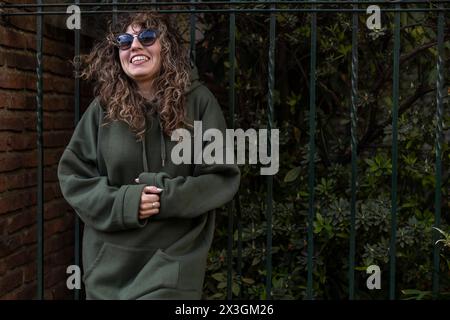 Junge lateinamerikanische Frau mit lockigen Haaren im Pullover, Sonnenbrille auf der Straße Stockfoto