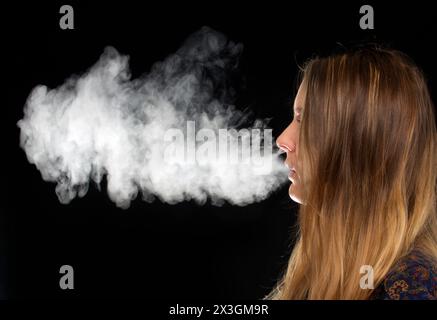 Frau, die Dampf ausatmet. Stockfoto