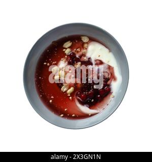 Ein Blick von oben auf eine Schüssel gefüllt mit Joghurt, gekrönt mit frischen roten Beeren und knusprigen Erdnüssen isoliert auf weißem Hintergrund mit Schneidepfad Stockfoto