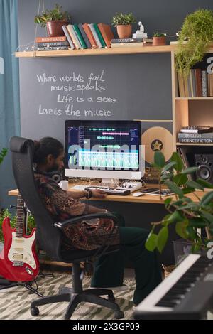 Seitenansicht eines müden jungen kreativen Mannes, der im Sessel am Arbeitsplatz mit Desktop-Computer sitzt und während der Arbeit ein Nickerchen oder eine kurze Pause macht Stockfoto